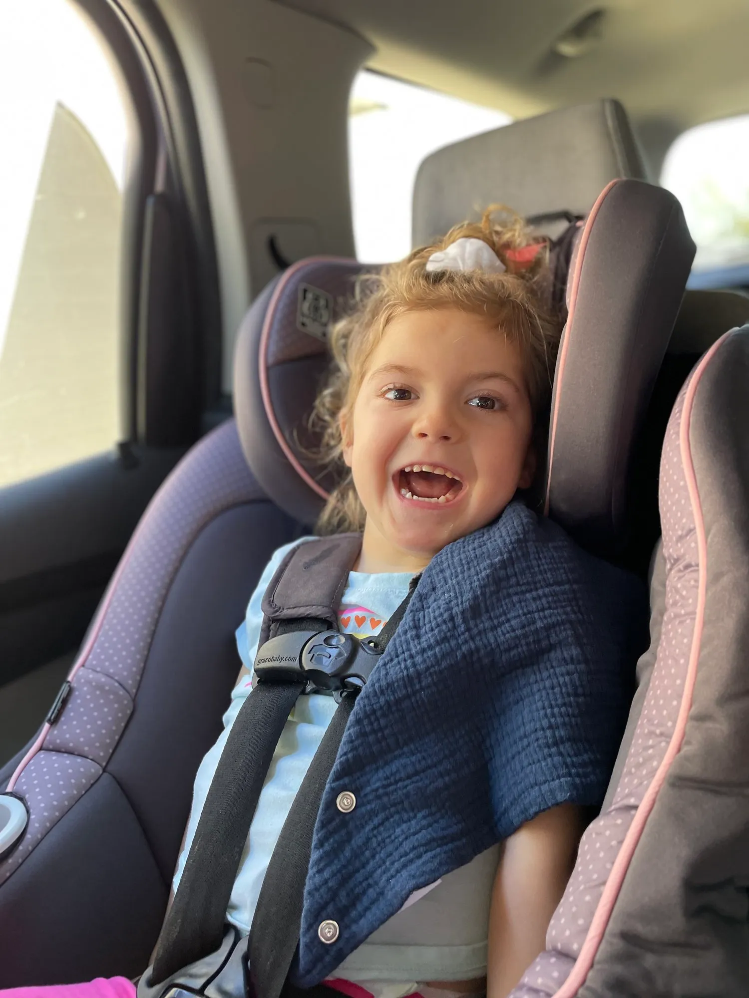 Lily Grace smiling brightly in her car seat.
